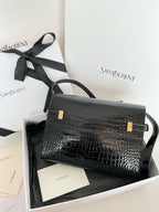 Crocodile-embossed handbag with black strap and gold front clasp, angled view