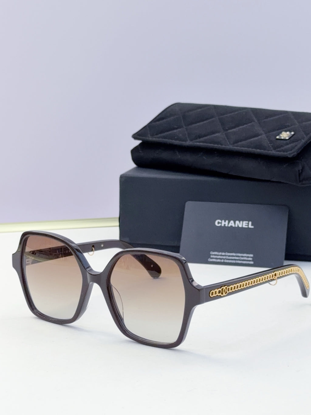 Eyeglasses with dark frame, warm brown lenses, gold chain temple, with case