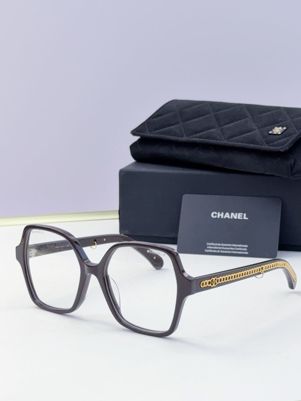 Eyeglasses with dark frame, clear lenses, gold chain temple, with case