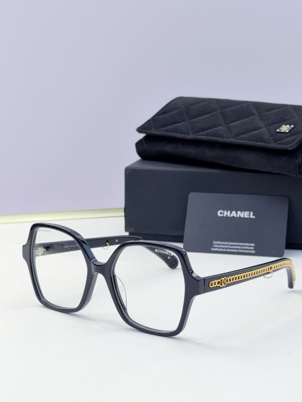 Eyeglasses with dark frame, clear lenses, gold chain temple, with case