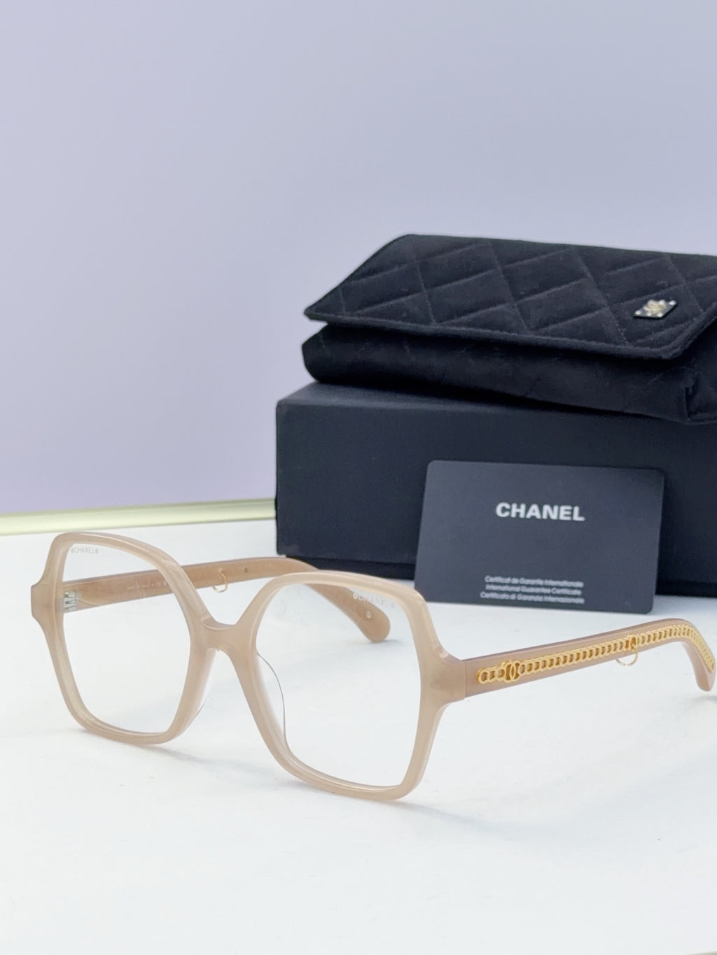 Eyeglasses with light beige frame, clear lenses, gold chain temple, with case