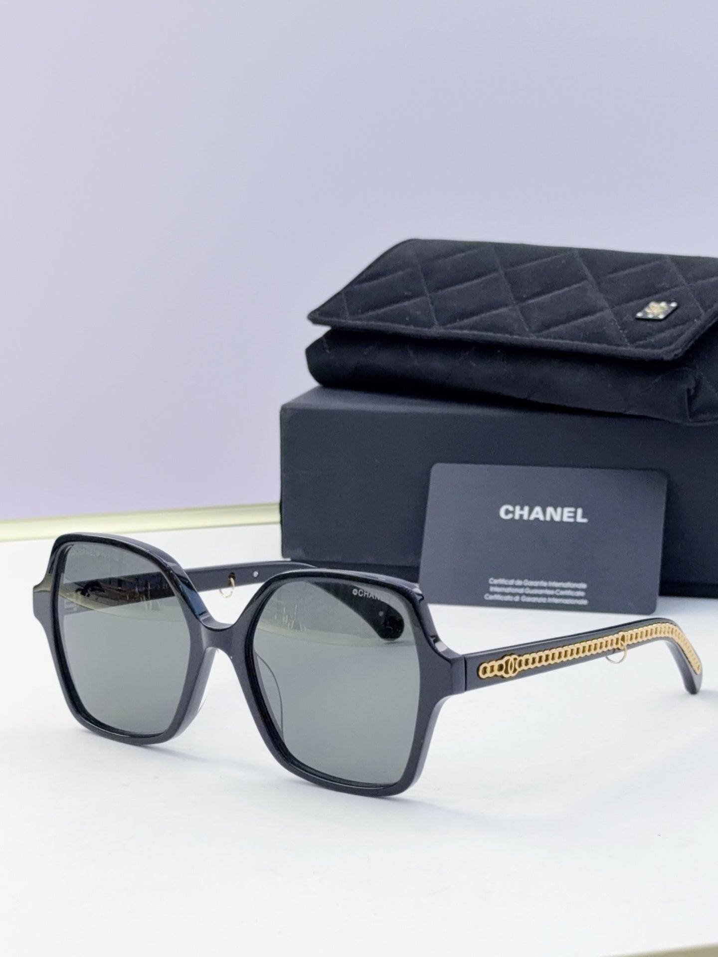 Eyeglasses with dark frame, tinted green lenses, gold chain temple, with case