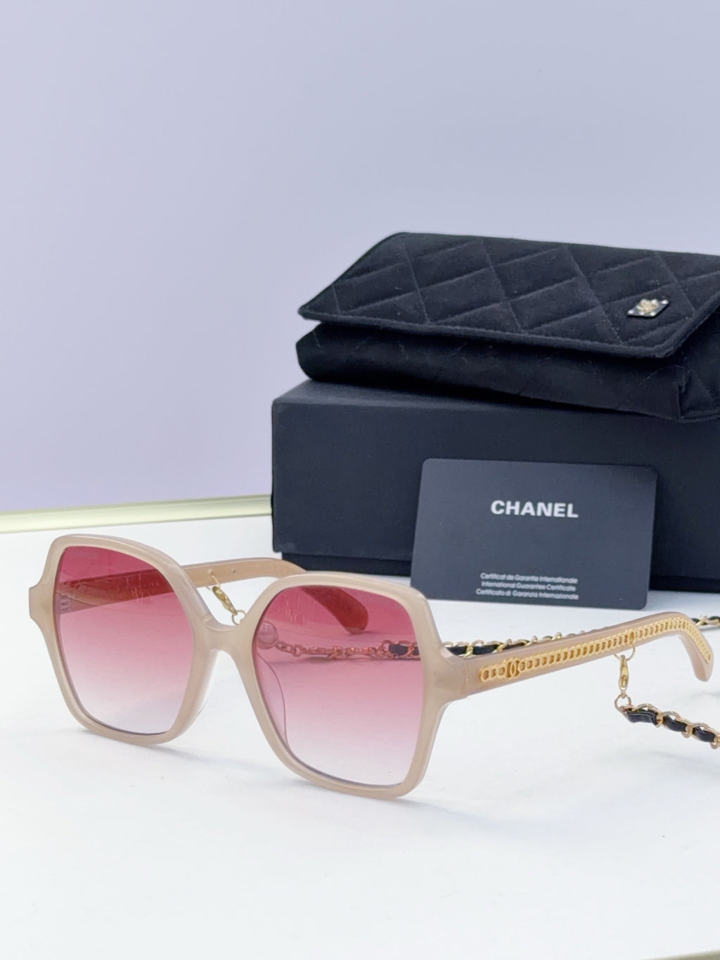 Eyeglasses with light beige frame, pink lenses, gold chain temple, with case