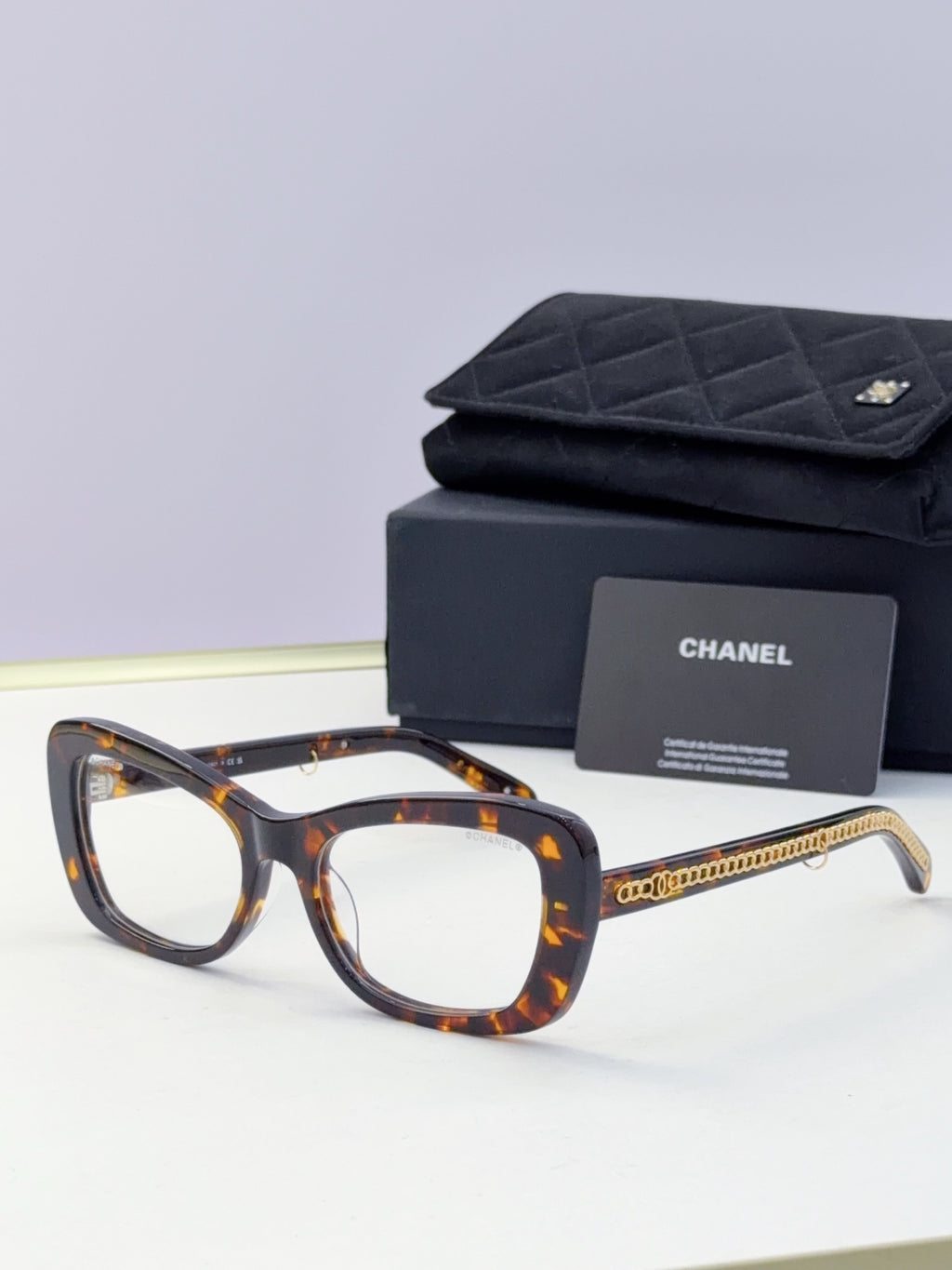 Tortoiseshell square sunglasses with orange-tinted lenses and gold chain temple detail
