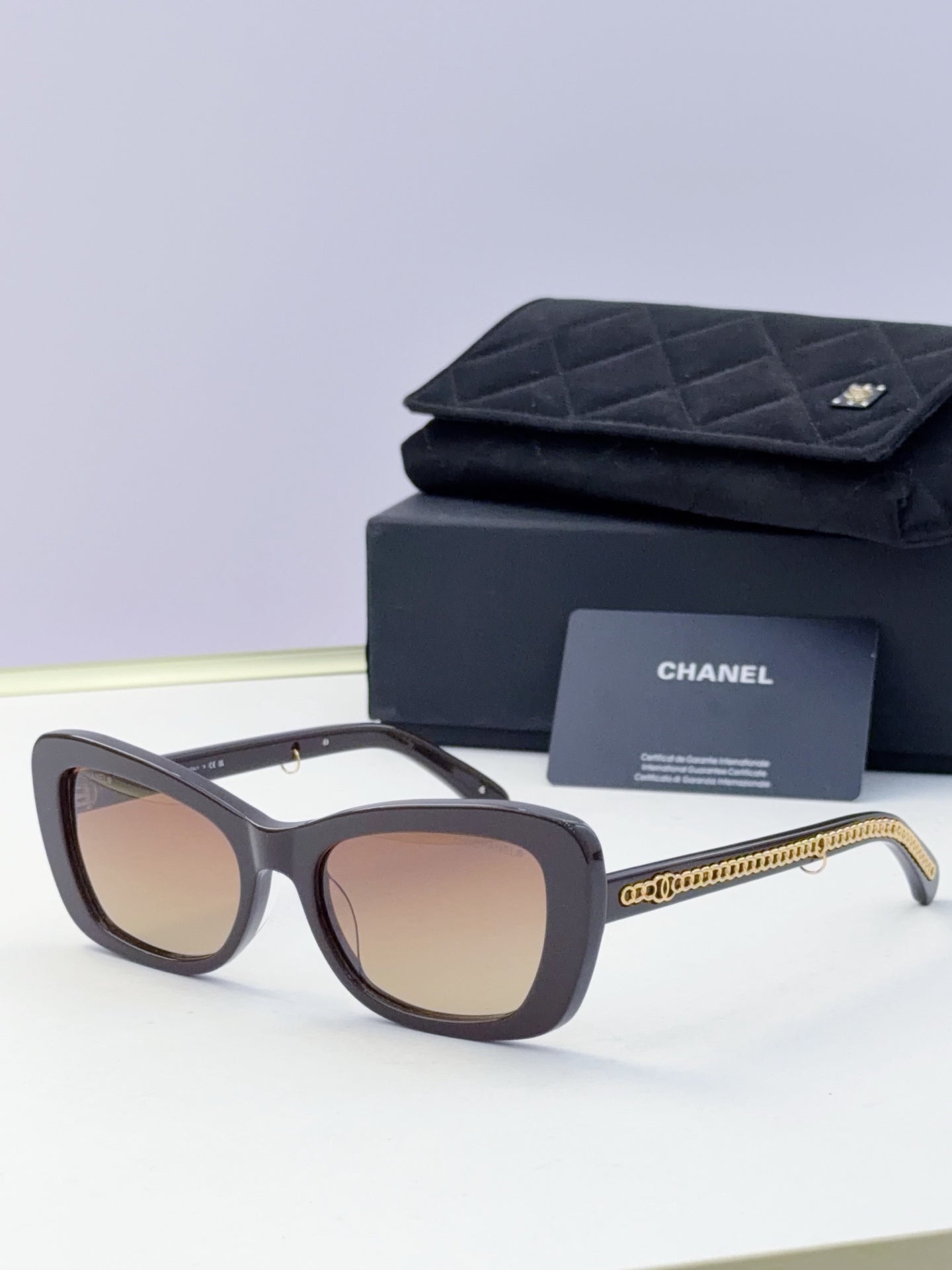 Brown square sunglasses with tan lenses and gold chain temples