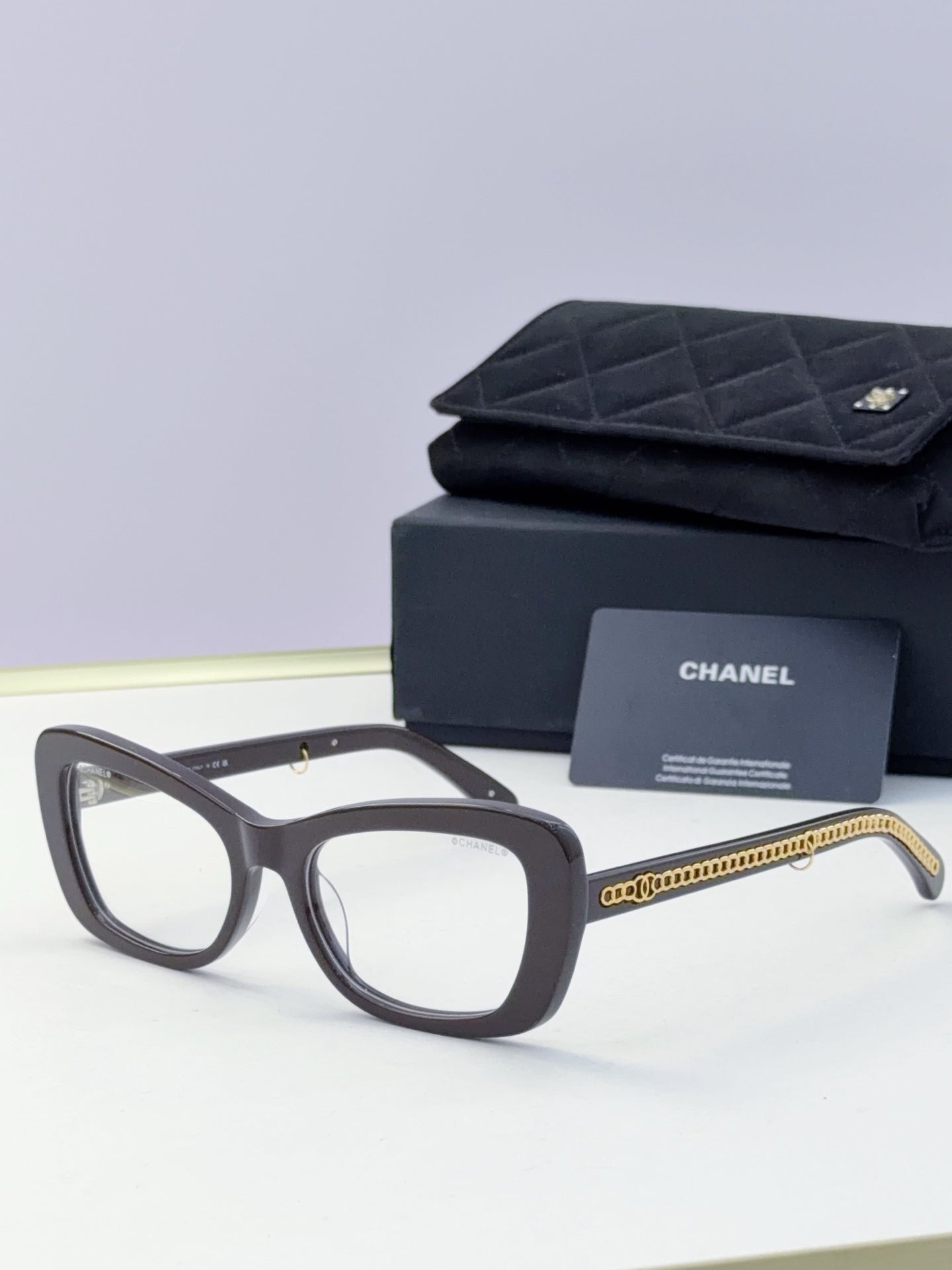 Black square sunglasses with clear lenses and gold chain temples