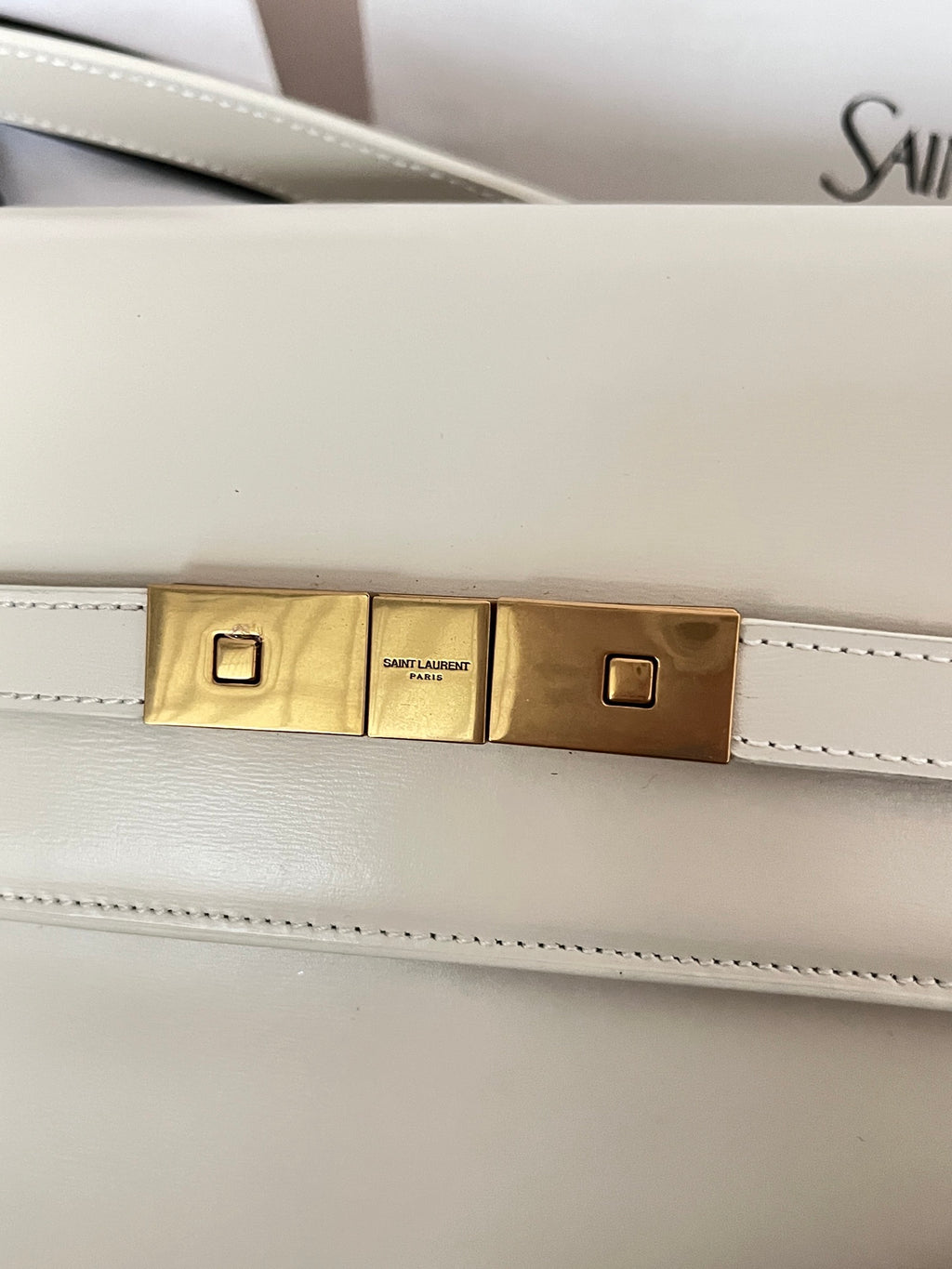 Ivory bag hardware bar with gold-tone center plates and stitched leather trim