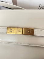 Ivory bag hardware bar with gold-tone center plates and stitched leather trim