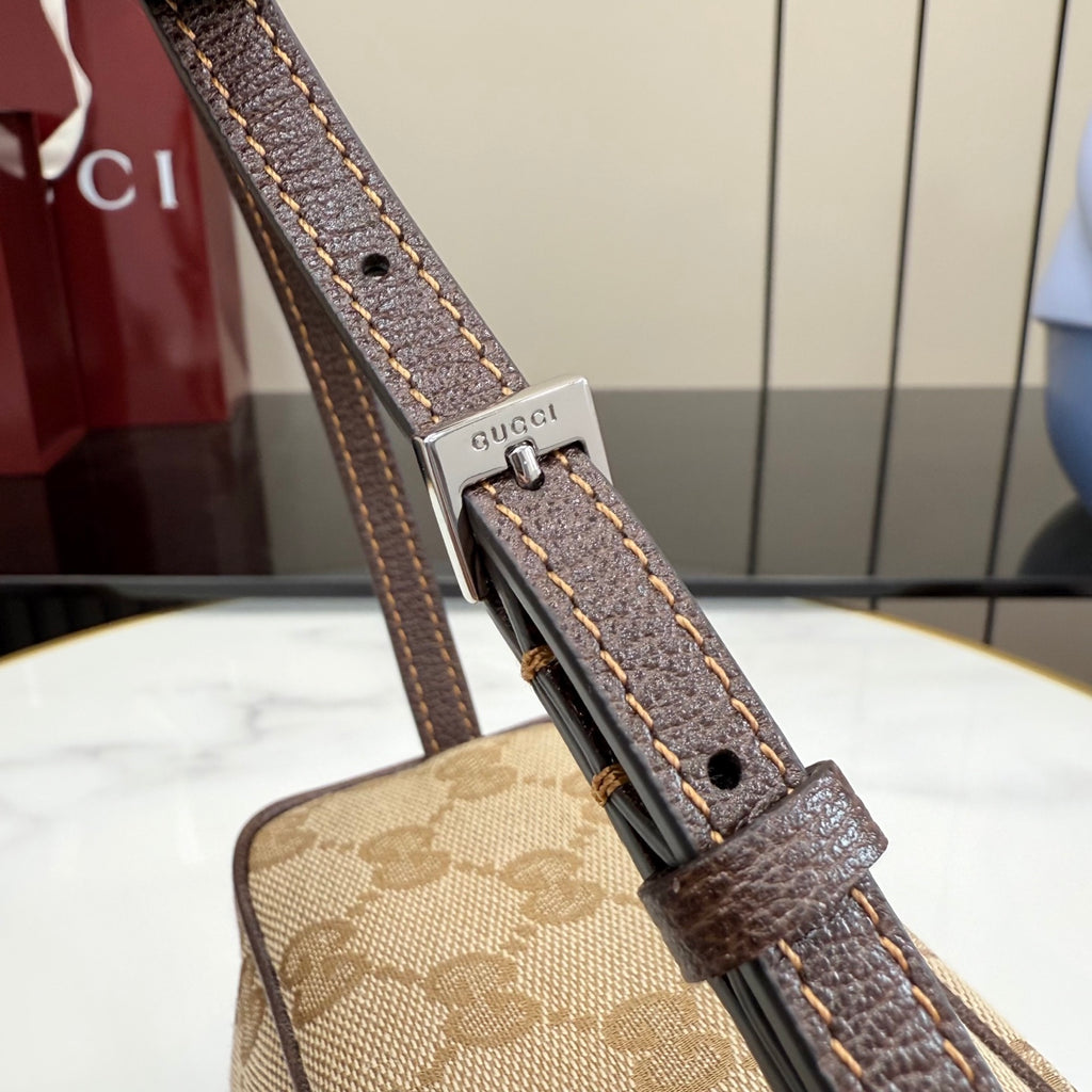 Handbag strap close-up with Gucci hardware, brown leather tab and adjustable buckle