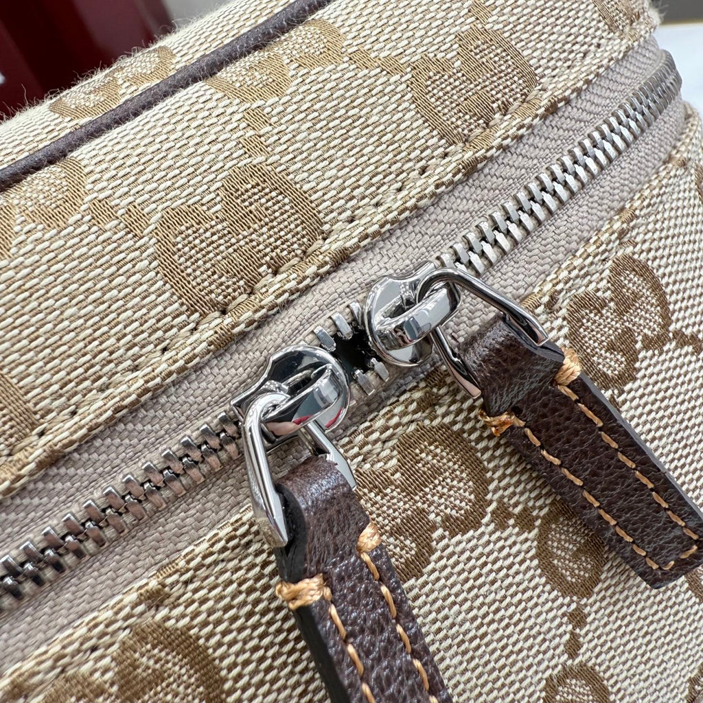 Handbag zipper close-up on beige GG canvas with silver zipper and dark leather tab