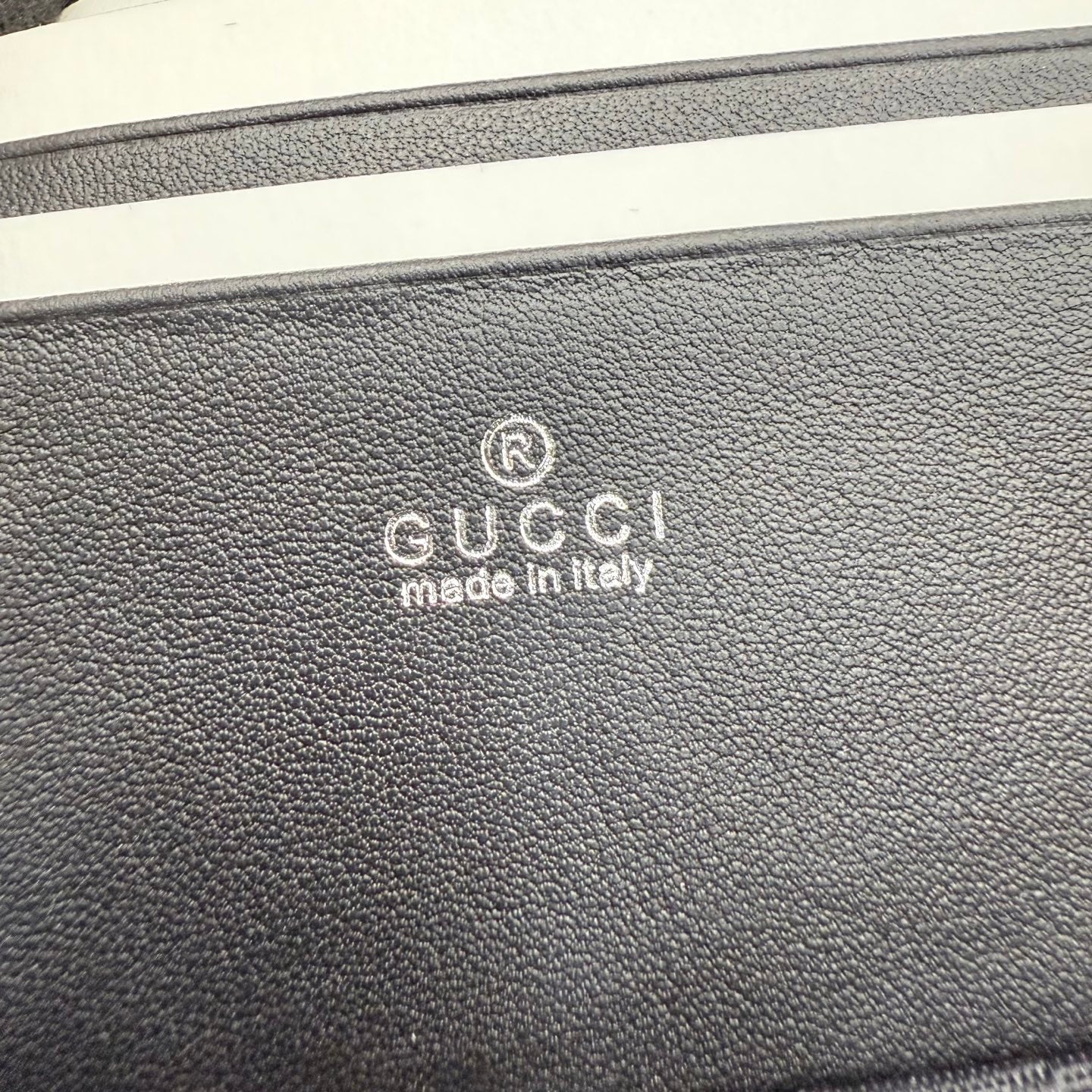 Black pebbled leather bag exterior with Gucci logo stamp and “made in Italy”