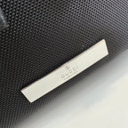 Gucci bag close-up with black textured fabric and silver Gucci logo plaque