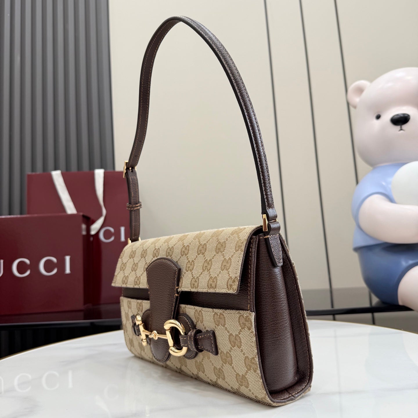 Gucci bag side view with GG canvas, dark leather top handle, and gold hardware accents