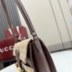 Designer bag close-up: brown leather top handle with gold clasp on beige canvas