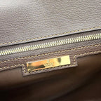 Gucci bag detail with gold logo plaque and zipper, dark leather exterior