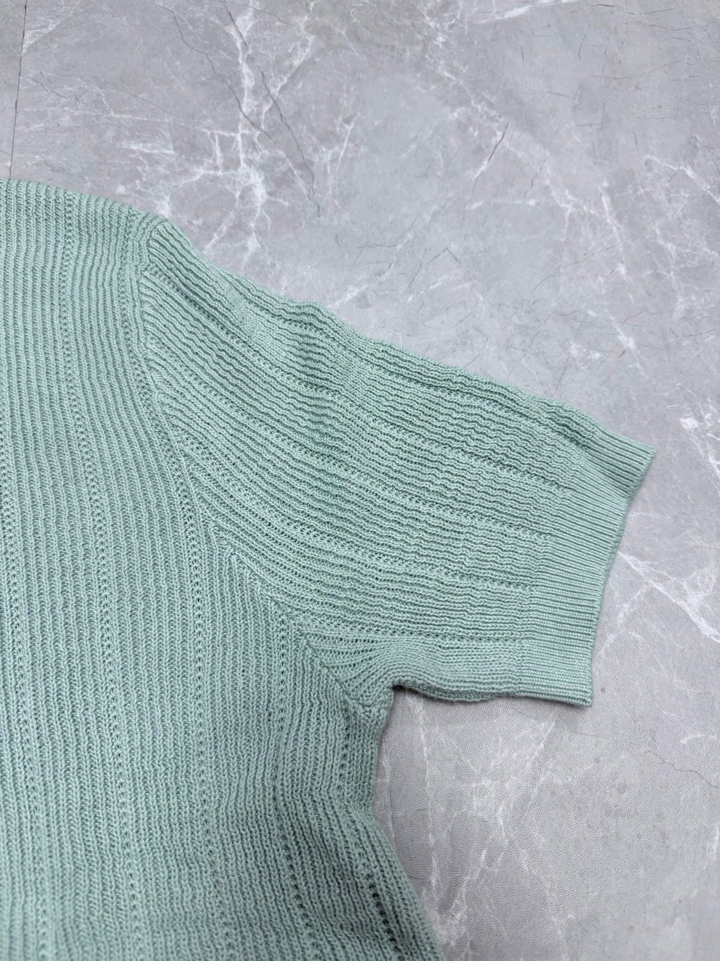 Light blue knit polo shirt sleeve with textured ribbed knit