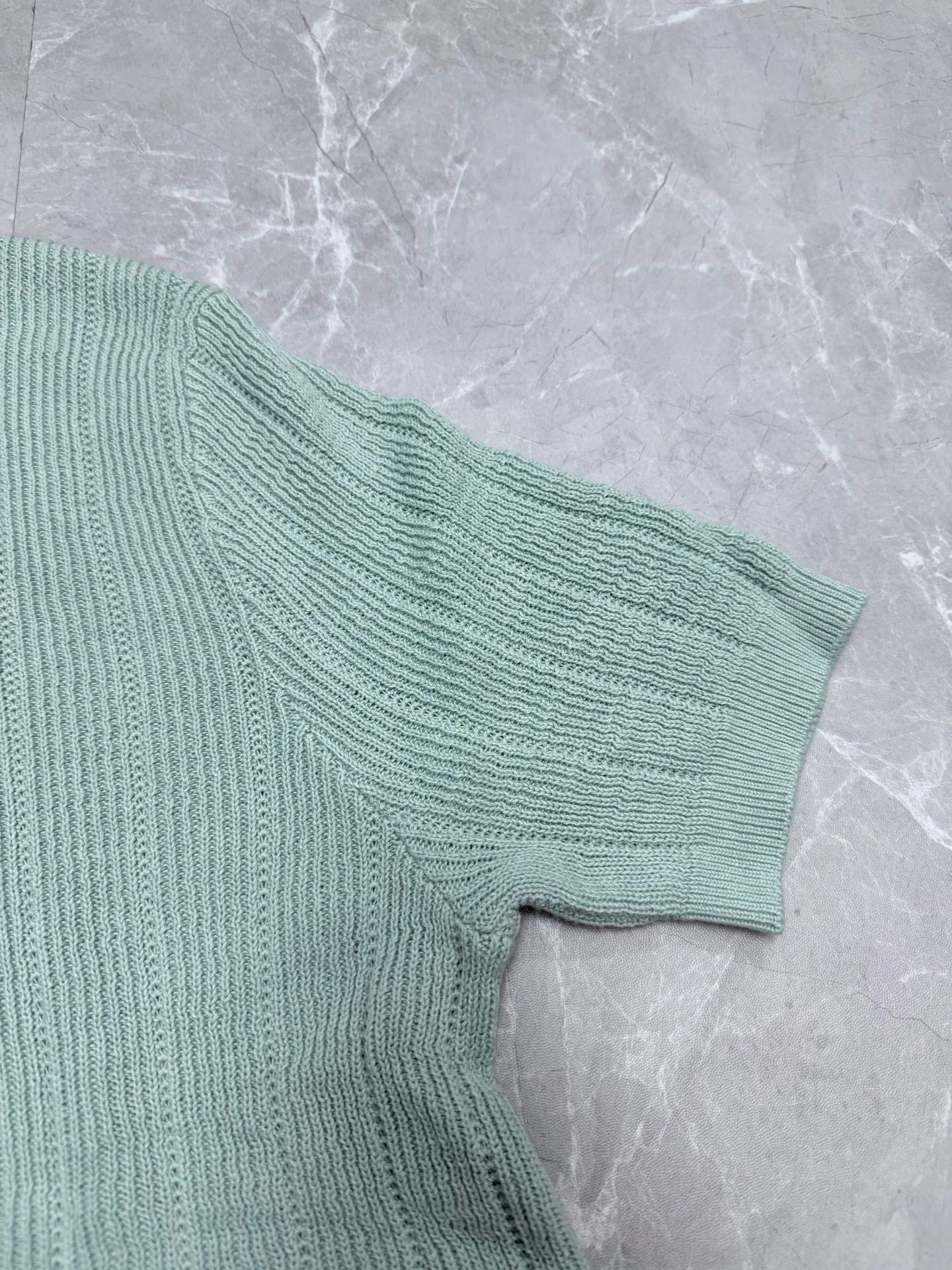 Light blue knit polo shirt sleeve with textured ribbed knit