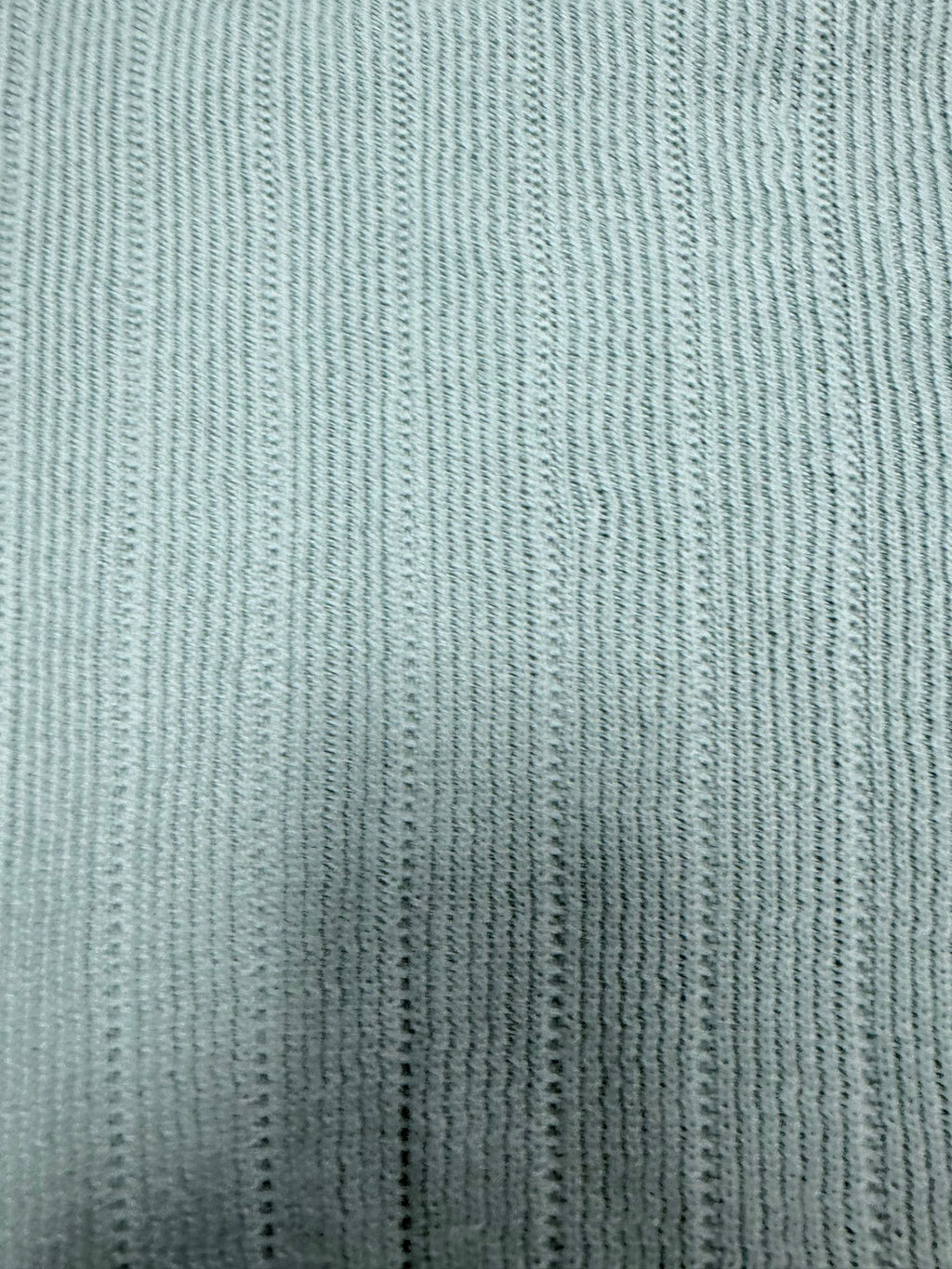 Light blue knit polo shirt fabric with fine vertical ribbed texture