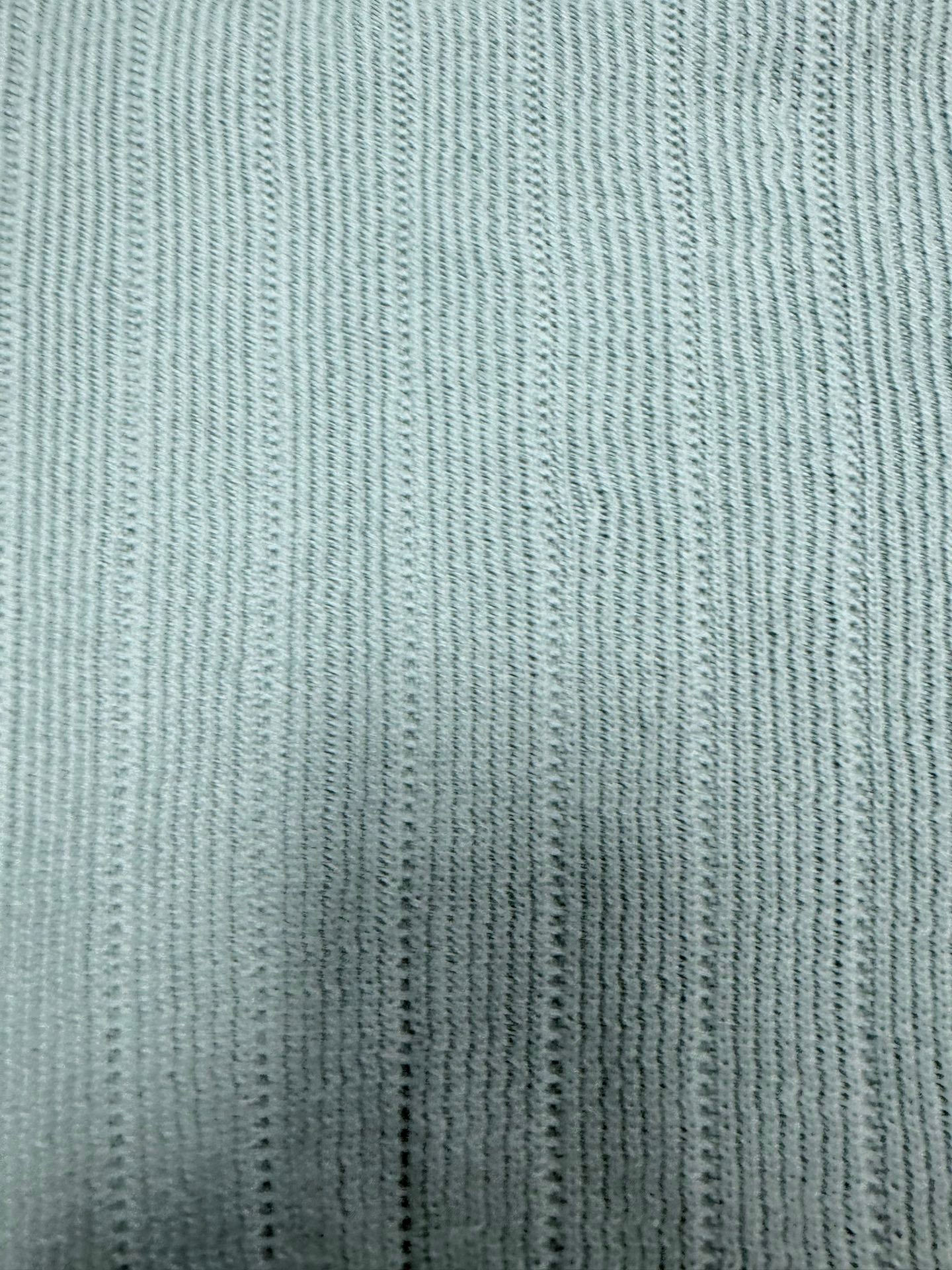 Light blue knit polo shirt fabric with fine vertical ribbed texture