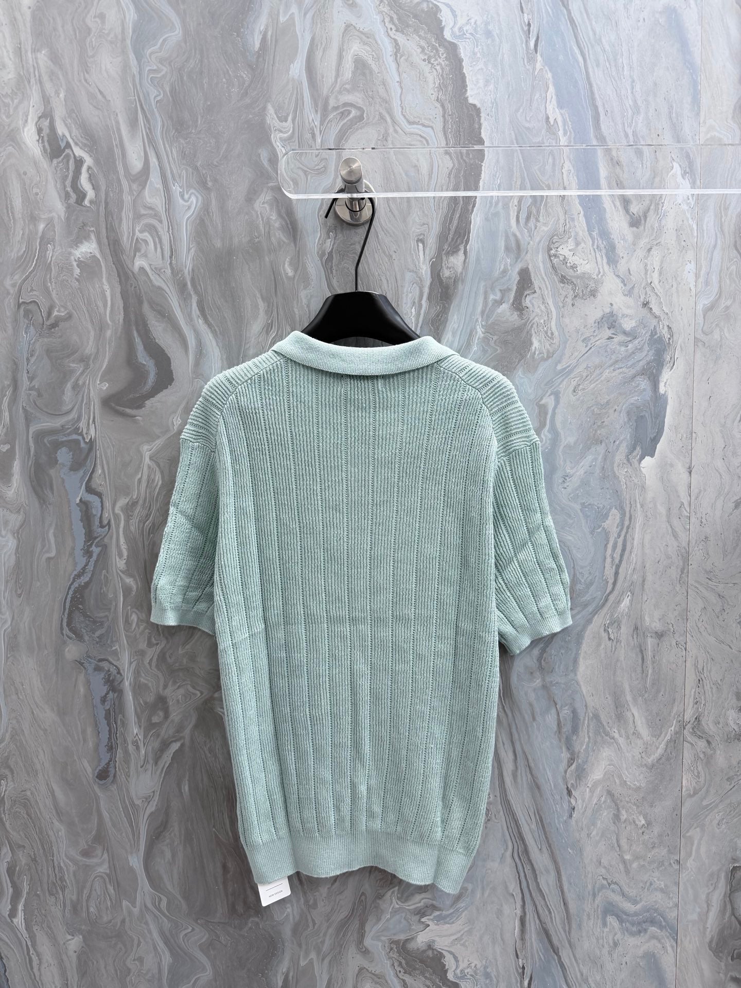 Light blue knit polo shirt with ribbed collar and short sleeves (back view)