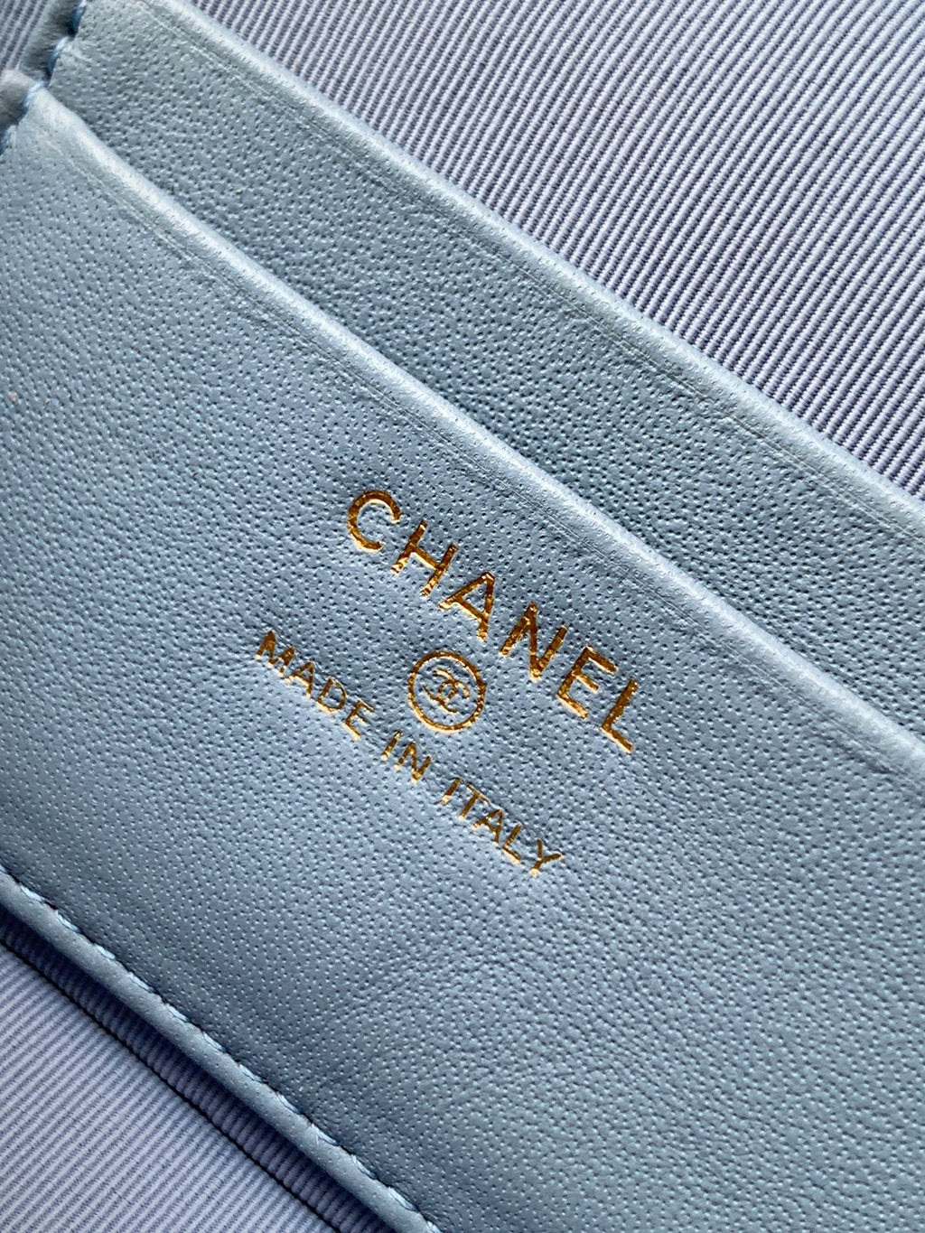 Chanel logo stamp on light blue fabric lining with gold-tone stitching