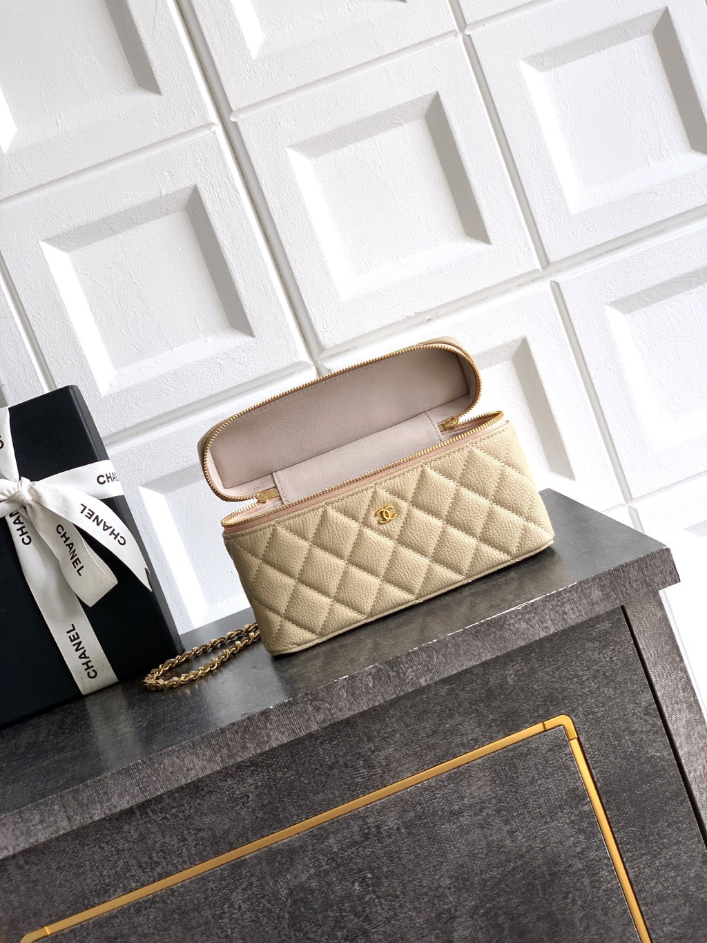 Light beige quilted handbag shown open with interior lining and gold zipper trim