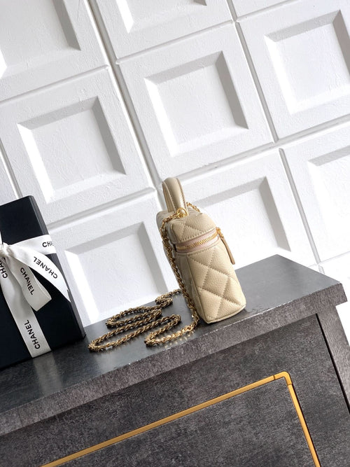 Light beige quilted handbag with top handle, gold hardware, and chain shoulder strap