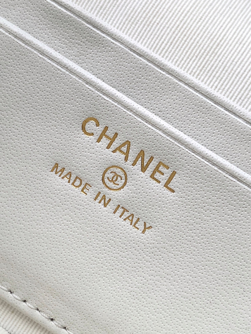 Close-up of white leather bag stamp: CHANEL MADE IN ITALY