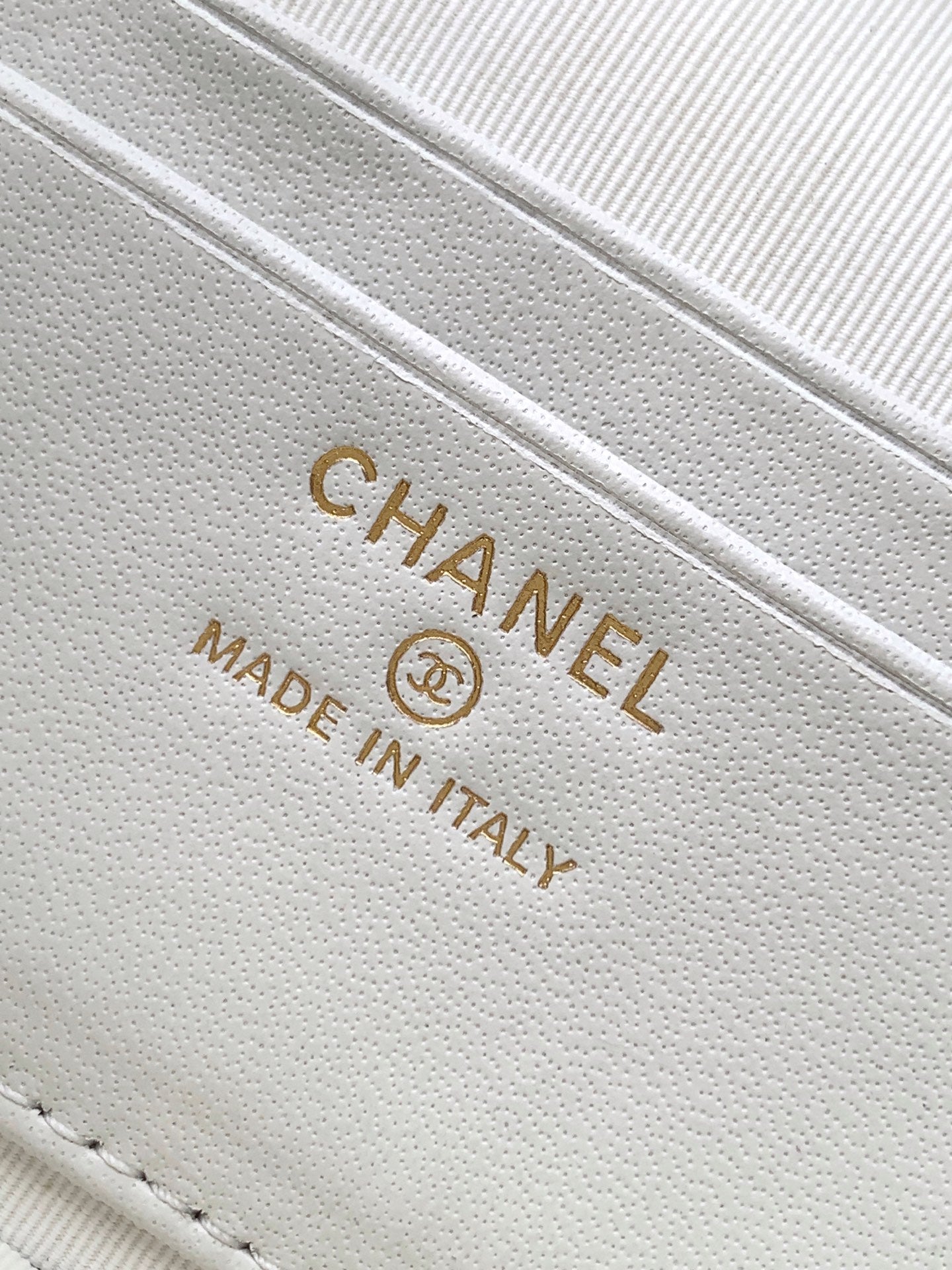 Close-up of white leather bag stamp: CHANEL MADE IN ITALY