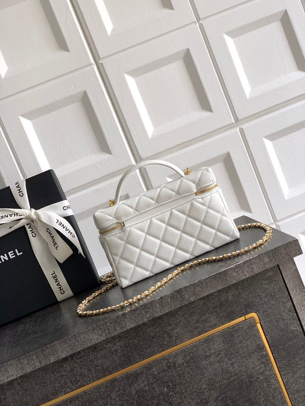 White quilted handbag with curved top handle and gold chain strap
