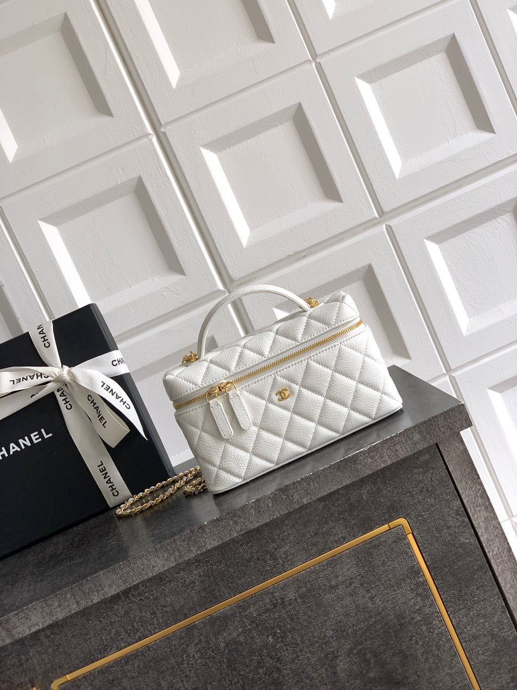 White quilted handbag with top handle and gold chain strap