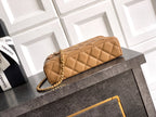 Tan quilted handbag with gold chain strap and zip top, stitched diamond pattern.