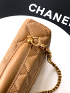 Tan quilted handbag close-up: zip pull tab and gold chain with hardware.