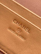 Tan quilted handbag close-up of embossed CHANEL logo on leather surface.