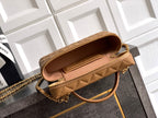Tan quilted handbag with zip top open, gold chain shoulder strap and tan handle.