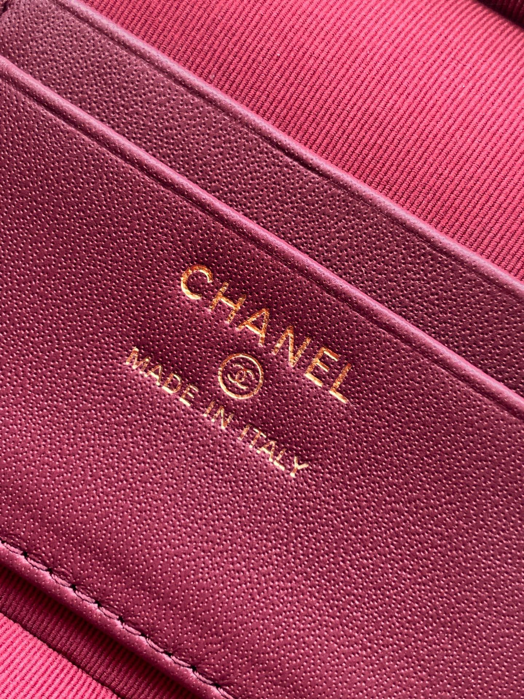 Chanel logo on burgundy leather strap with embossed text and stitching