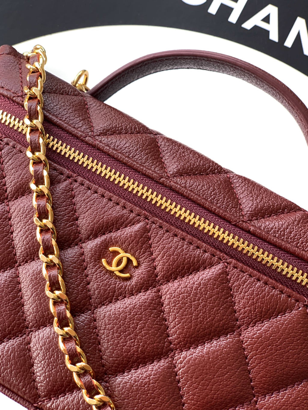 Chanel quilted leather bag close-up in burgundy with gold zipper pull and CC logo