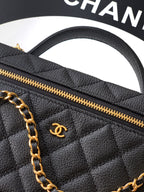 Black quilted handbag close-up showing gold zipper and gold Chanel emblem.