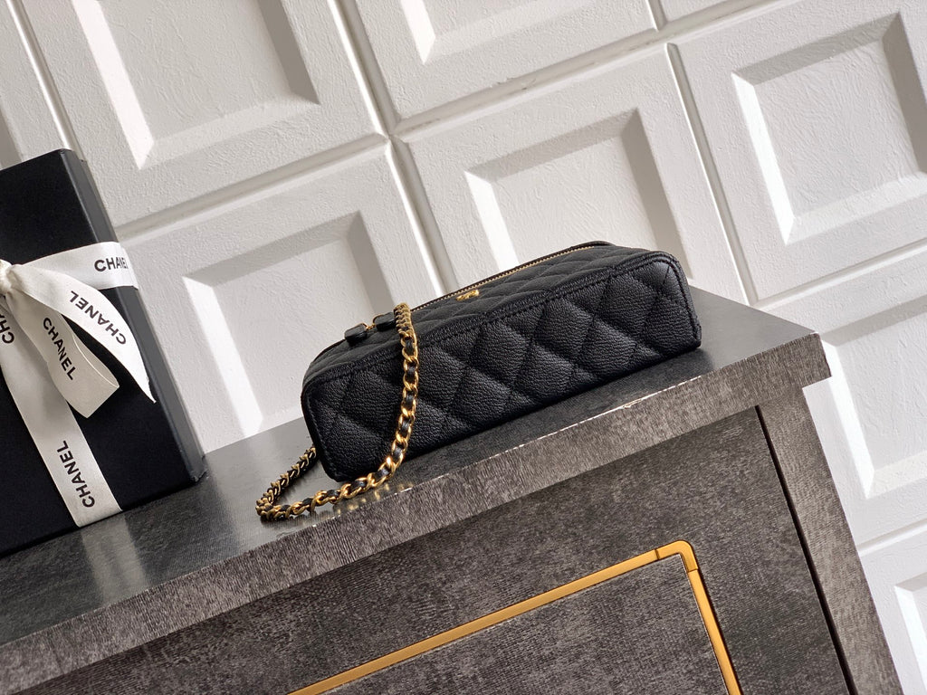 Black quilted mini handbag with gold chain strap and curved top handle, zip closure.