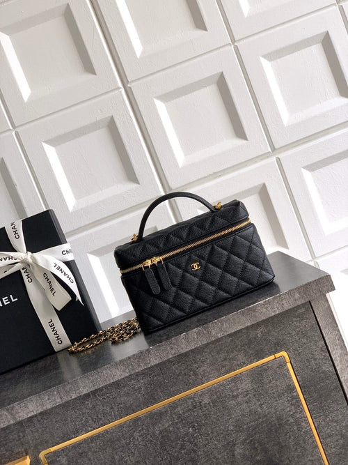 Black quilted handbag with gold chain strap and top handle, zip closure.