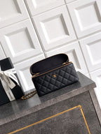 Black quilted handbag with gold chain strap and zip top, small logo plaque.