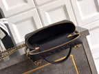 Black quilted handbag with zip-top opening and gold chain strap.