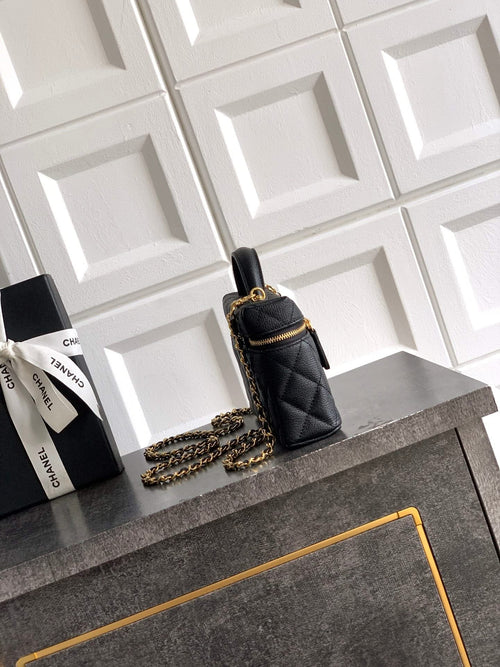 Black quilted mini handbag with gold chain strap and top handle, zip closure.