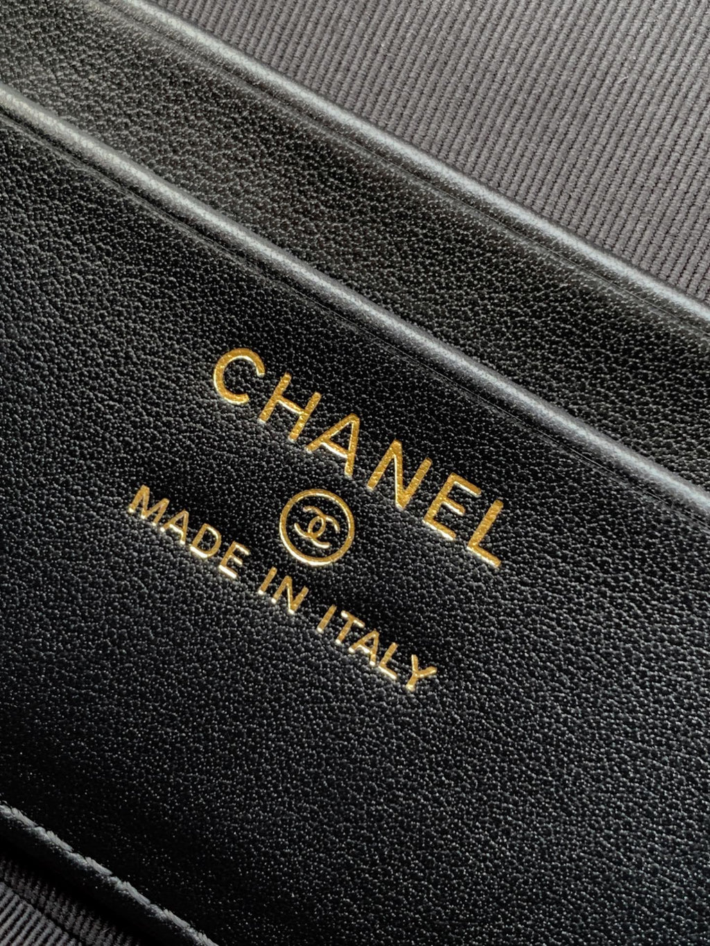 Close-up of black leather handbag with CHANEL and Made in Italy stamp.