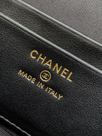Close-up of black leather handbag with CHANEL and Made in Italy stamp.