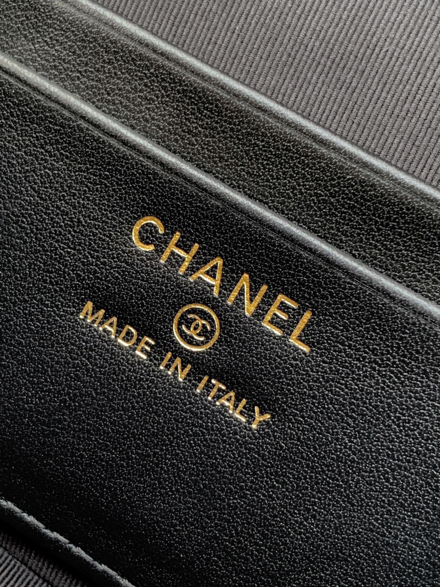 Close-up of black leather handbag with CHANEL and Made in Italy stamp.