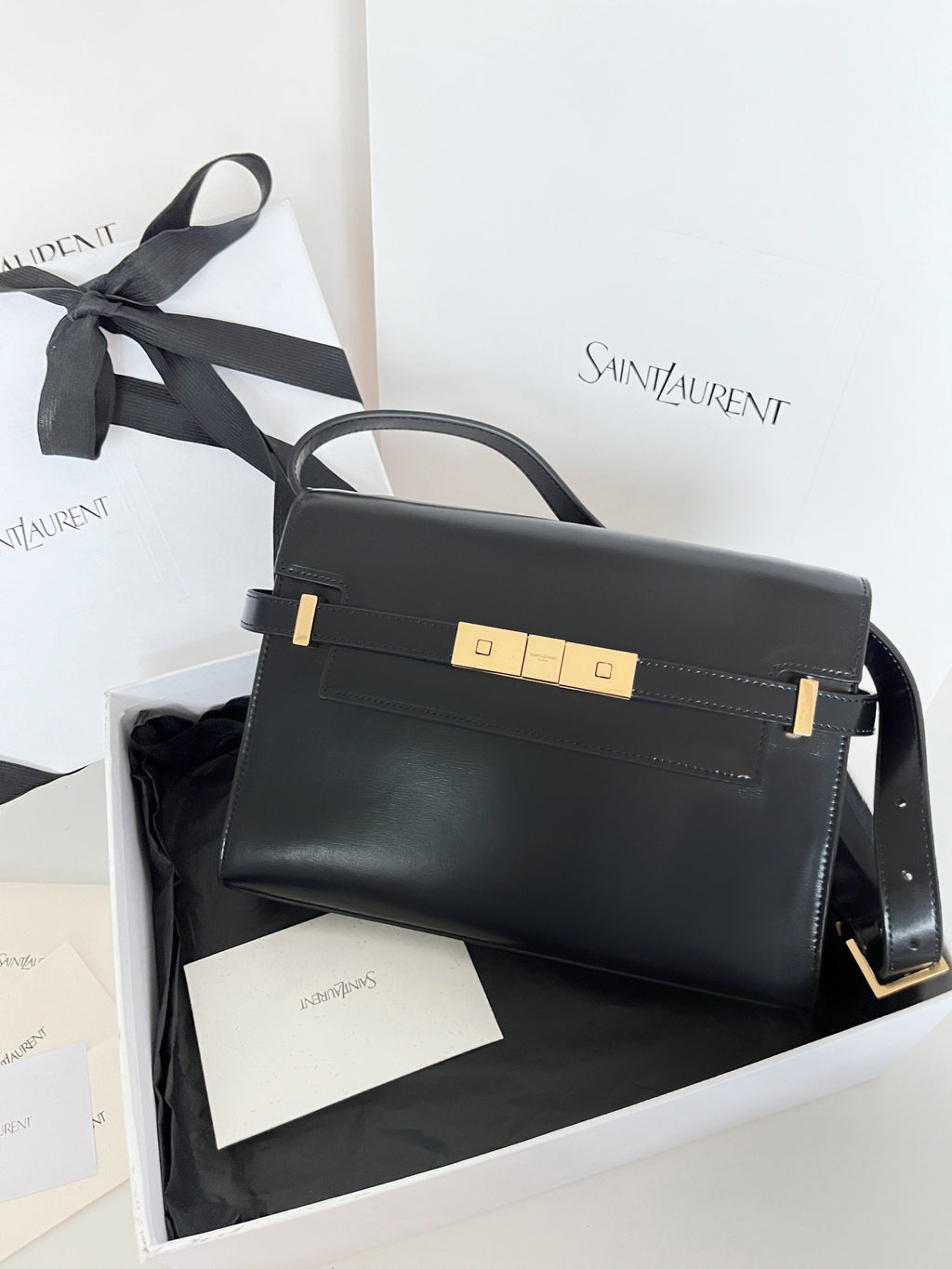 Black YSL structured handbag with gold-tone front closure and top handle