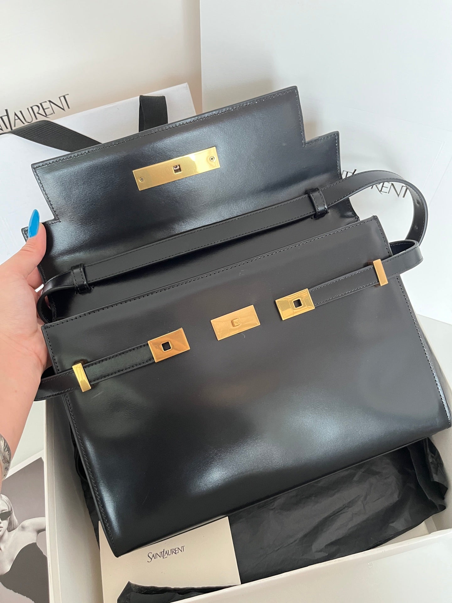 YSL handbag top view in dark leather with gold-tone front lock and straps