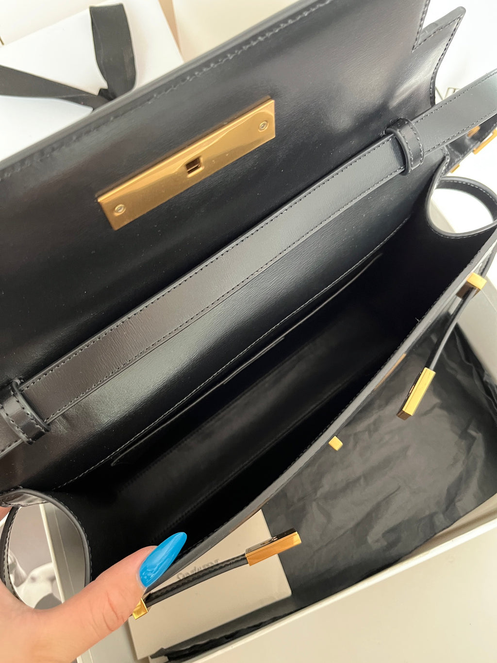 YSL handbag side view with gold-tone lock plate and dark leather interior