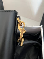 Dark gray leather tote bag close-up of gold carabiner clasp and side hardware
